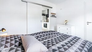 A bedroom with a bed, a nightstand, a dresser, and a sliding door leading to a kitchen. - Apartment '2' with Wi-Fi (Weddingstedt/OT Weddinghusen)