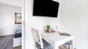 A room with a bed, a white table with a magazine, a plant, and a TV on the wall. - Apartment '2' with Wi-Fi (Weddingstedt/OT Weddinghusen)