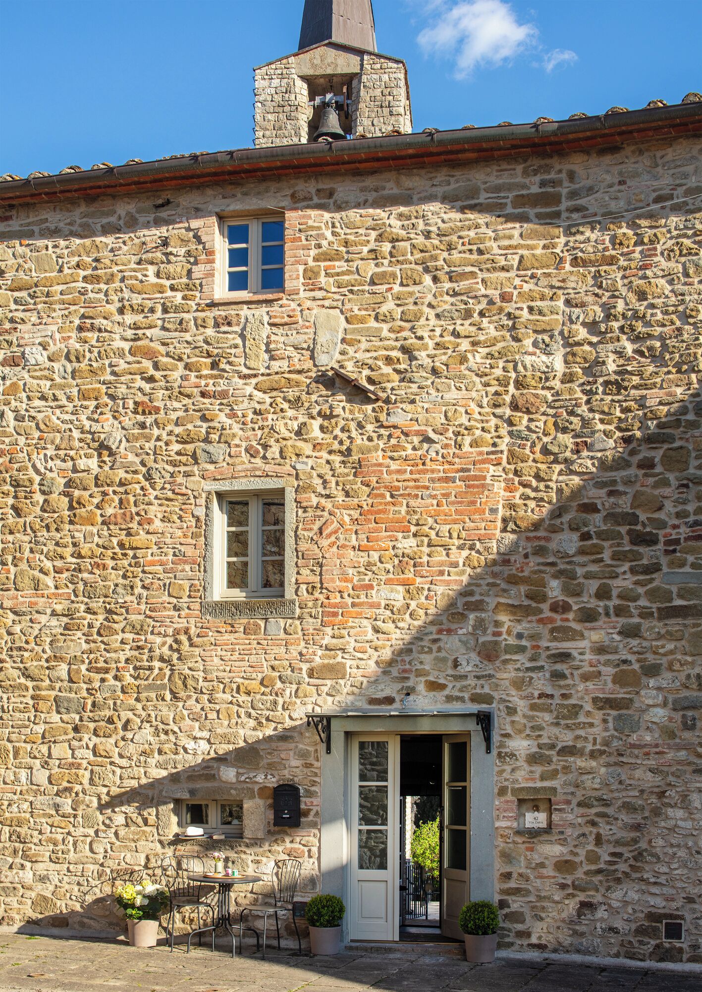 Un edificio in pietra con un campanile, un portone e una piccola finestra.
