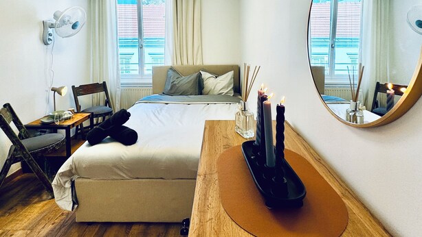 Een hotelkamer met een bed, een bureau, een stoel, een spiegel en een raam met gordijnen.