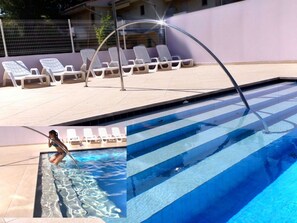 A swimming pool with clear blue water, a tiled deck, and white lounge chairs. - Relaxing Apartment in Bibione-beahost (San Michele al Tagliamento)