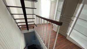 A staircase with a wooden handrail and white walls. - Cosy 3-bedroom house - ideal for families and groups (Brionne)