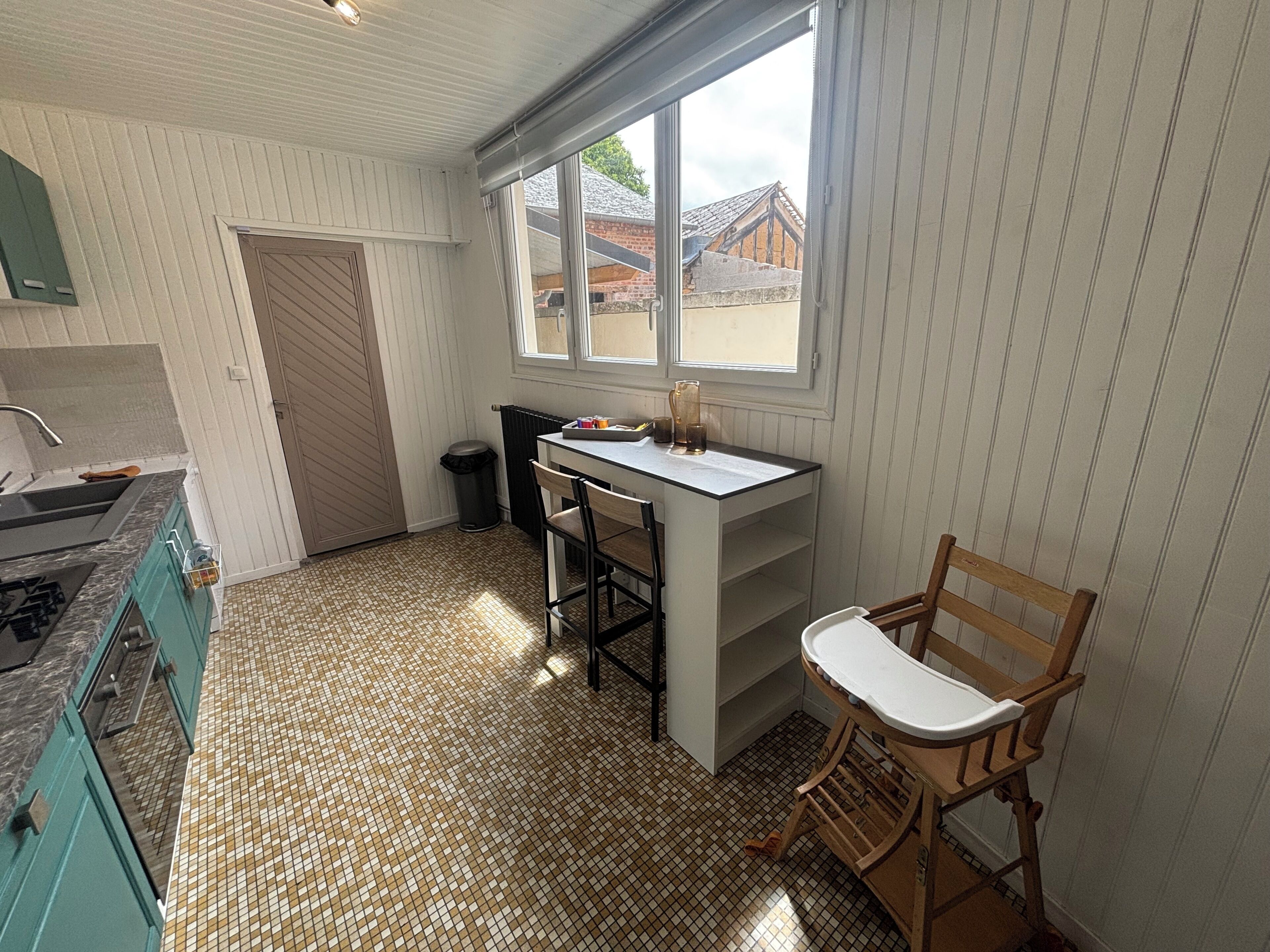 A kitchen with a tiled floor, a window with a view, a sink, and a stove.