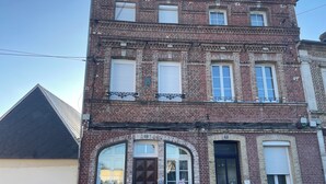 A two-story brick building with a flat roof, large windows, and a small balcony. - Cosy 3-bedroom house - ideal for families and groups (Brionne)