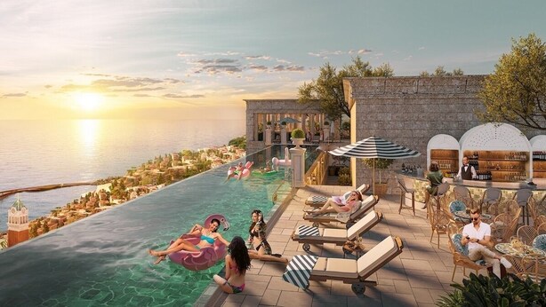 An infinity pool with clear water, a bar area with seating, and a view of the sea and buildings. - CITY APARTMENT SUNSET TOWN (Phu Quoc)