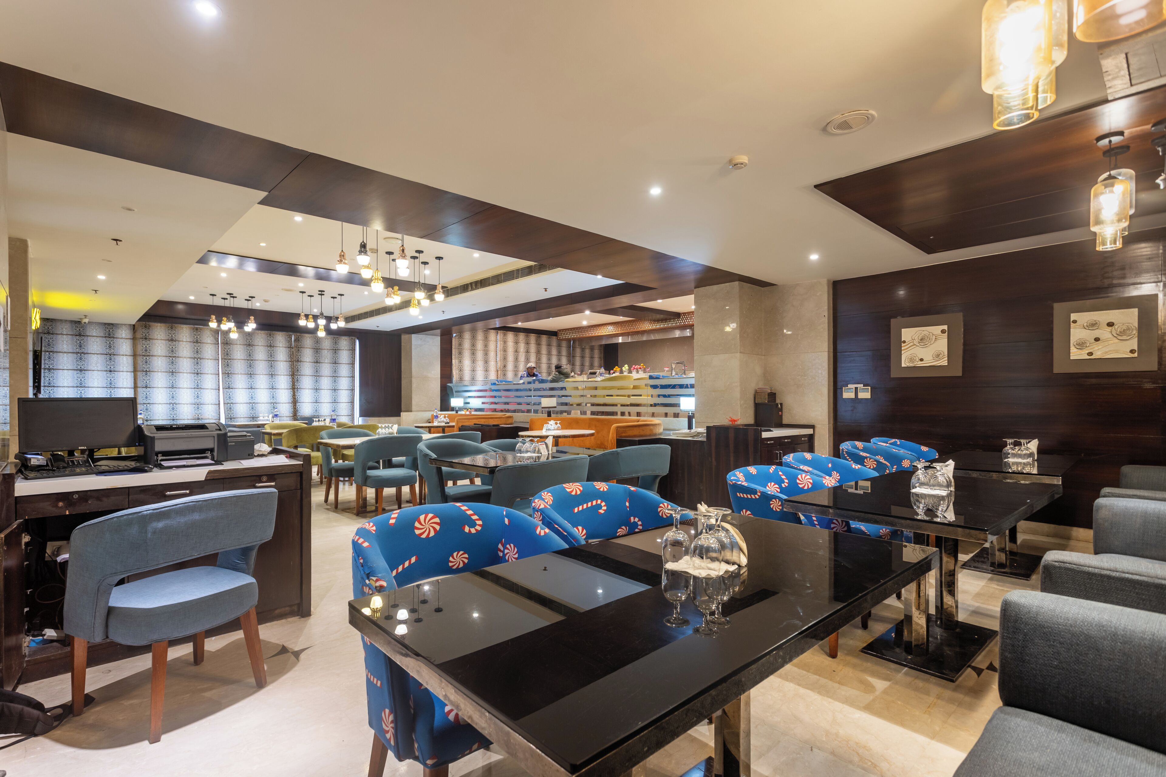 A modern hotel lobby with a reception desk, seating area, and a bar.
