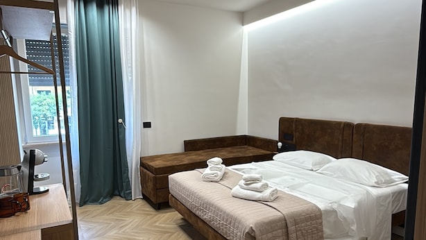 A modern bedroom with a bed, bedside tables, a mirror, and a window with curtains. - ULIVO GUEST HOUSE ROME (Rome)