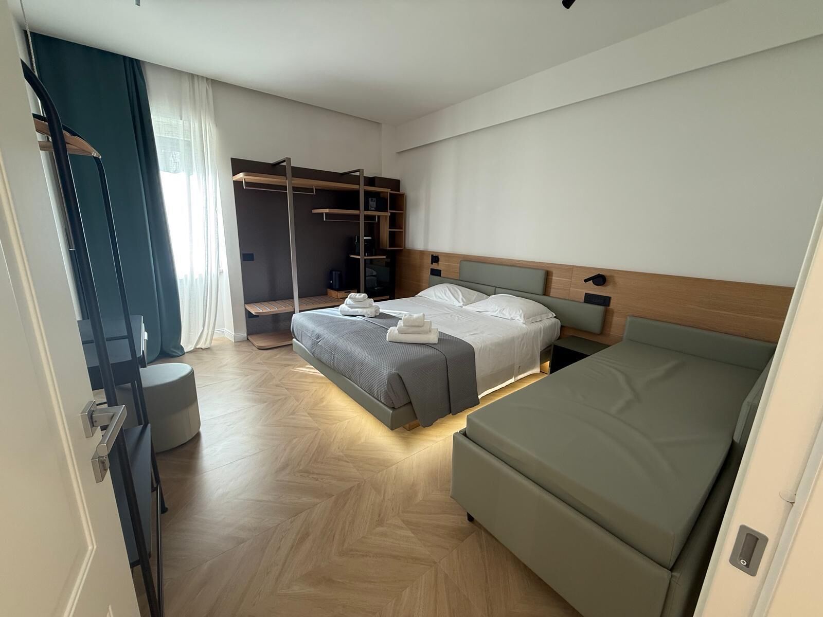 Et moderne hotelværelse med seng, sofa, garderobeskab og spejl.