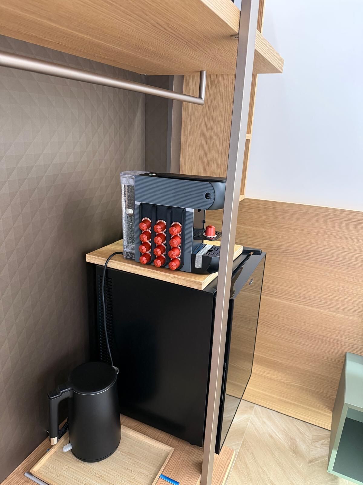 Une petite cuisine équipée d’une machine à café, d’une bouilloire et d’un petit placard.