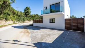 Ein modernes, zweistöckiges Haus mit Balkon, Auffahrt und Holzzaun.