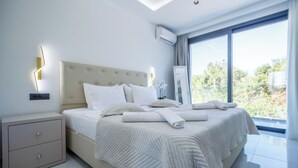 Ein modernes Schlafzimmer mit einem großen Bett, einem Nachttisch, einem Spiegel und Blick auf Grünfläche.