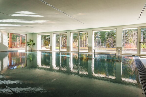 Ein großes Hallenbad mit Panoramafenstern und Blick auf Bäume.