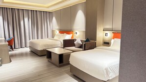 A hotel room with two beds, a sofa, a small table, and a chair. - Amaris Hotel (Barka)