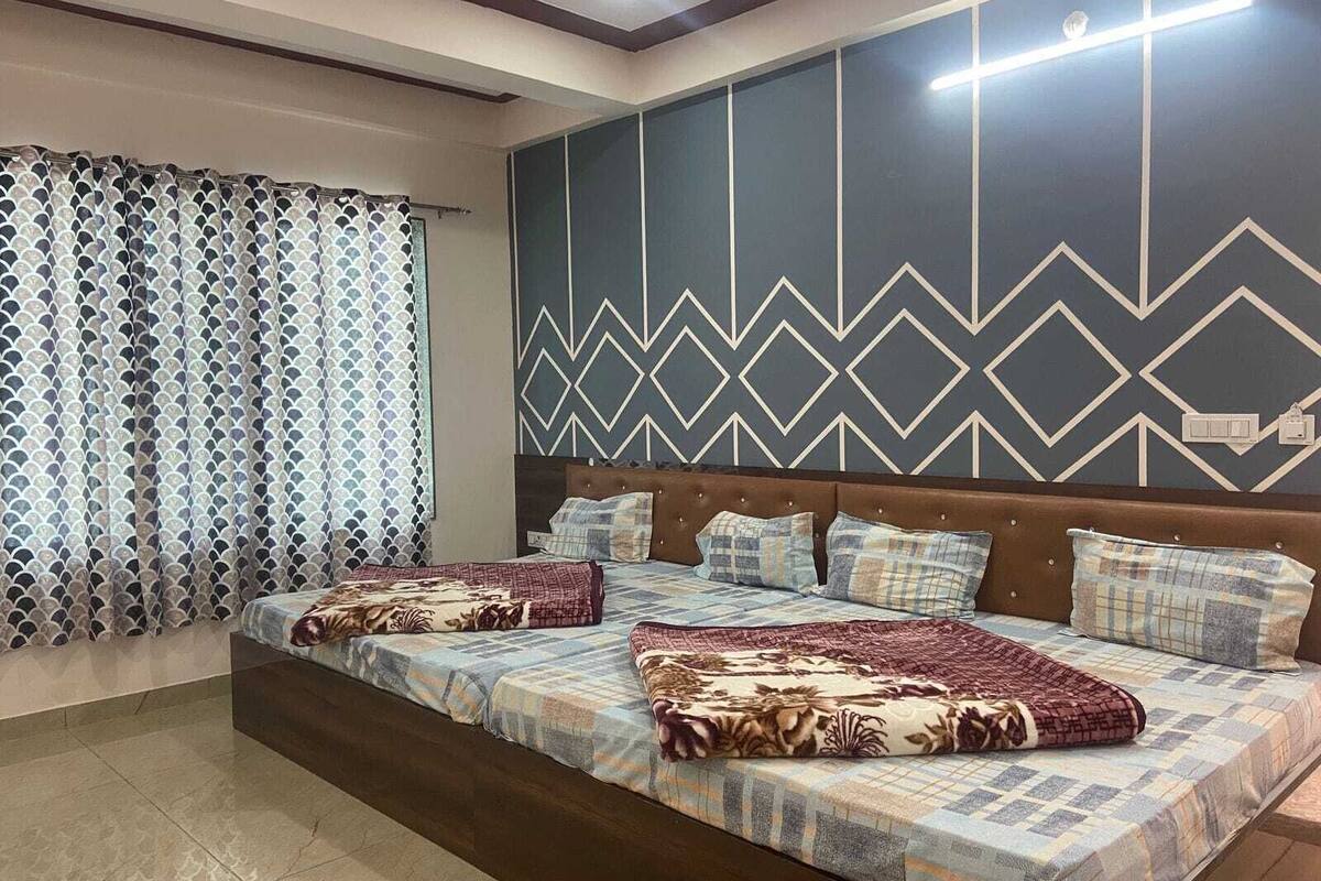 Une chambre à coucher avec un lit, des rideaux à motifs, un motif géométrique sur le mur et un luminaire moderne au plafond.