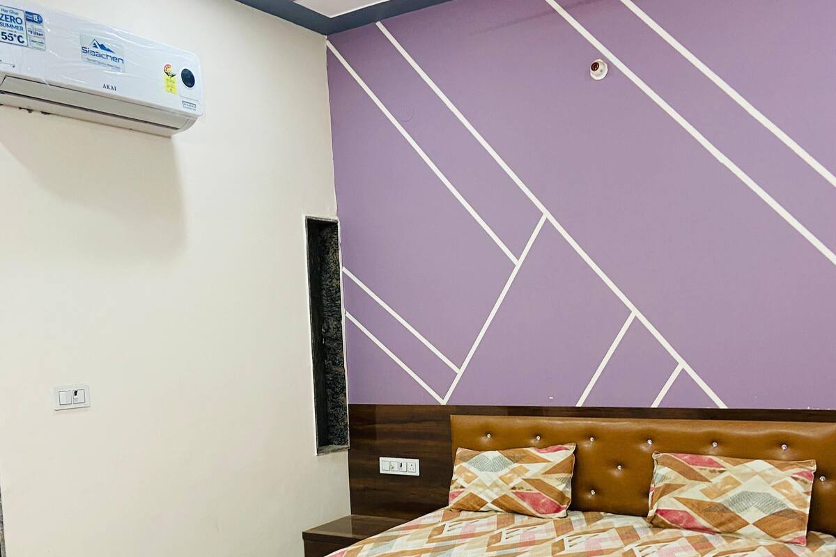 Une chambre à coucher comprenant un lit, un ventilateur de plafond, un appareil de climatisation et une table de chevet.