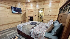 Une chambre à coucher de style cabane en bois, avec un lit, un téléviseur fixé au mur et une petite table.