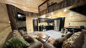 L’intérieur de ce chalet accueillant comprend un espace de vie avec deux canapés en cuir, une table basse et une cheminée. La cuisine est équipée d’appareils modernes et dispose d’un coin repas.