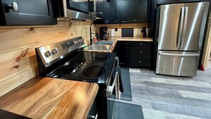 Une cuisine moderne avec des meubles de couleur noire, des appareils en acier inoxydable et un plan de travail en bois.