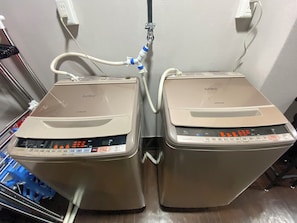 Two Hitachi appliances, likely washing machines, connected to a power outlet and a water source.