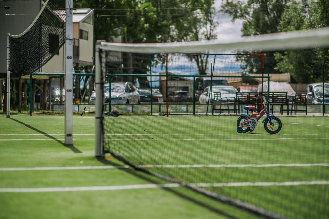 Un terrain de sport avec un but protégé par un filet, un vélo et des voitures garées en arrière-plan.