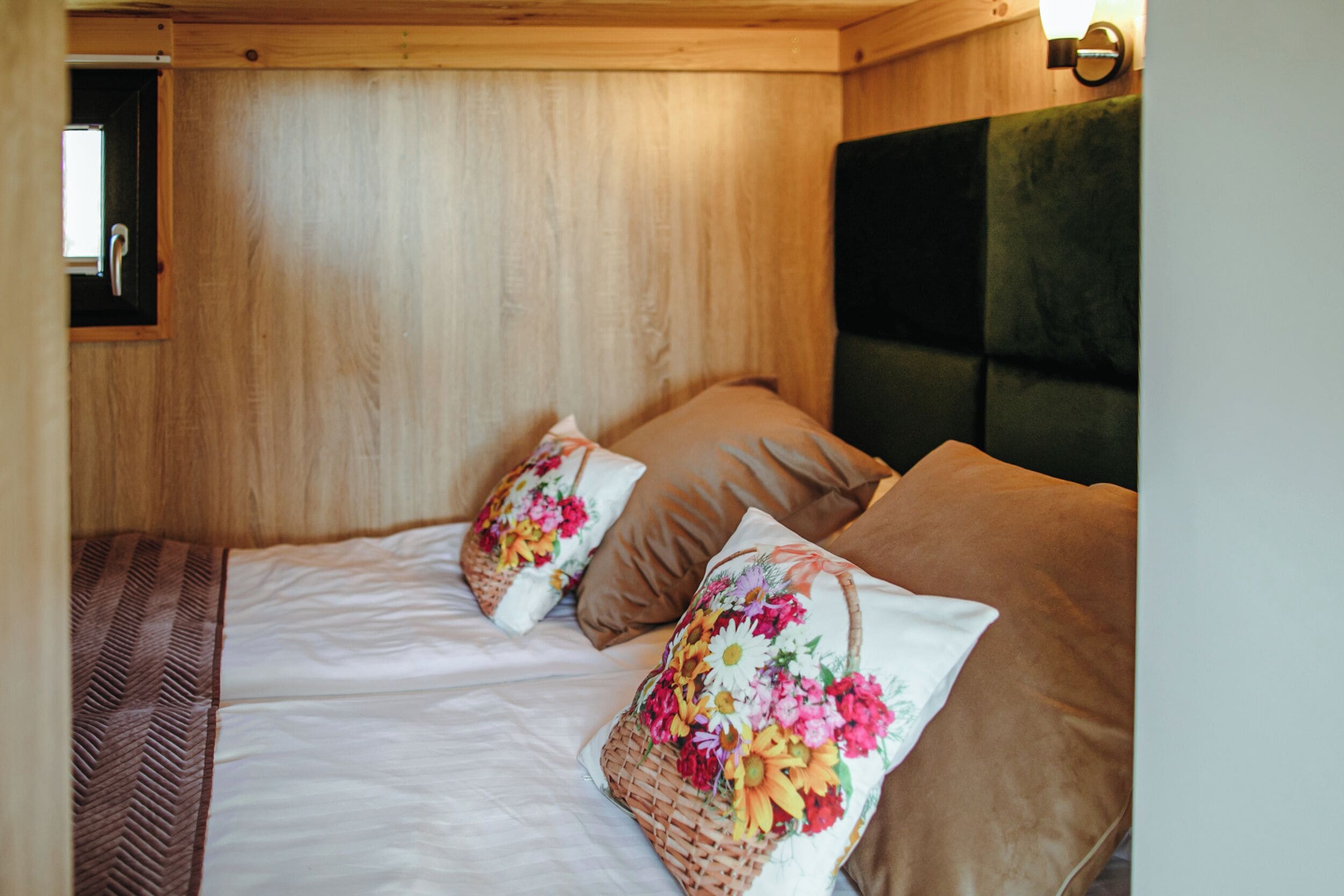 A wooden-paneled bedroom with a bed, two pillows, and a nightstand.