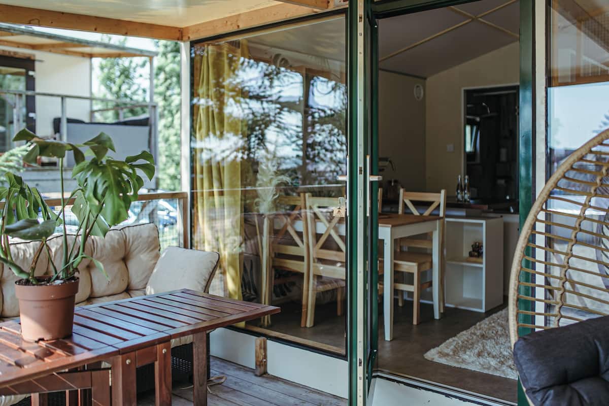 Um espaço acolhedor no interior, com uma mesa de madeira, cadeiras e um vaso com planta.