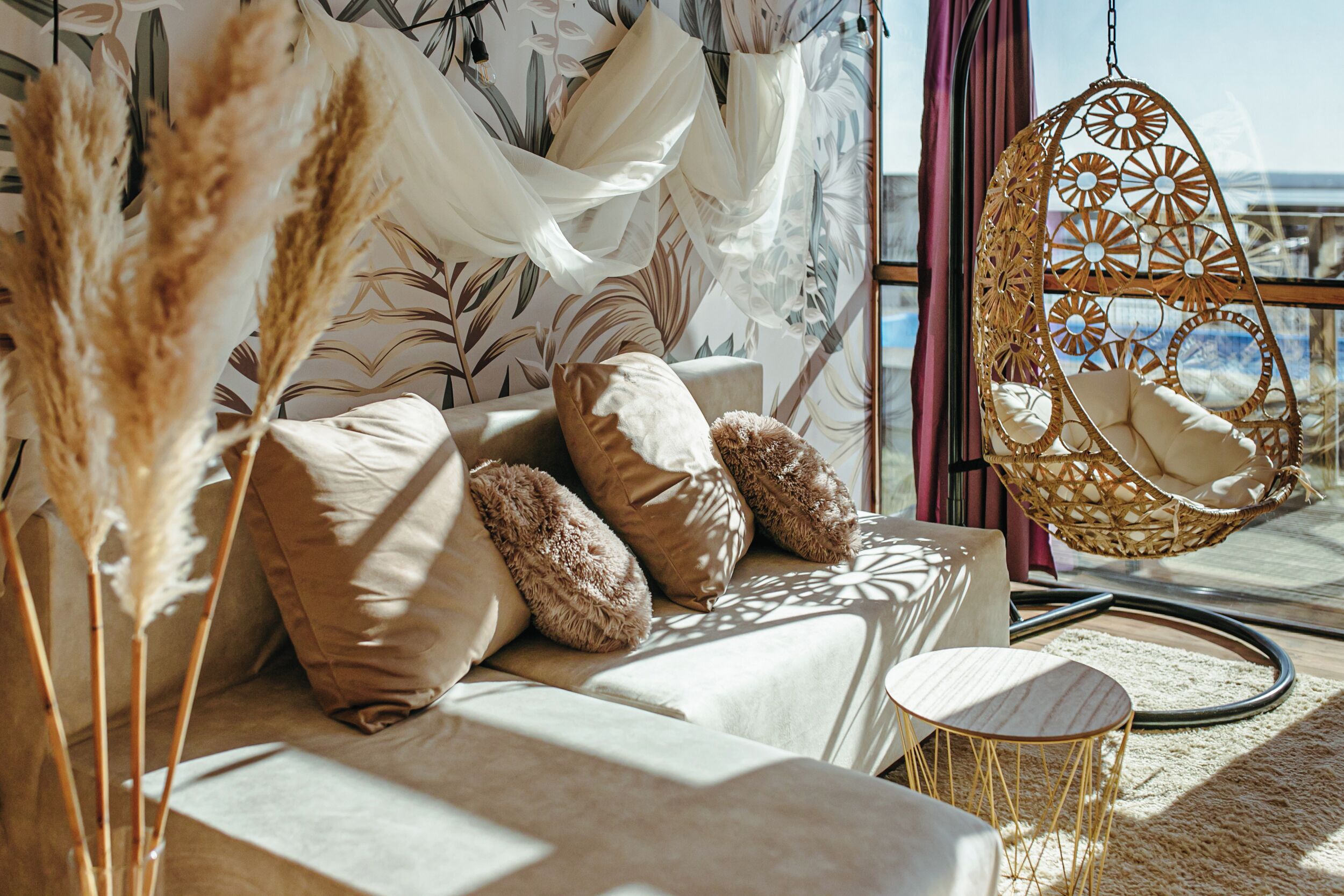 A cozy room with a cushioned seating area, a hanging chair, and a view of the outdoors.