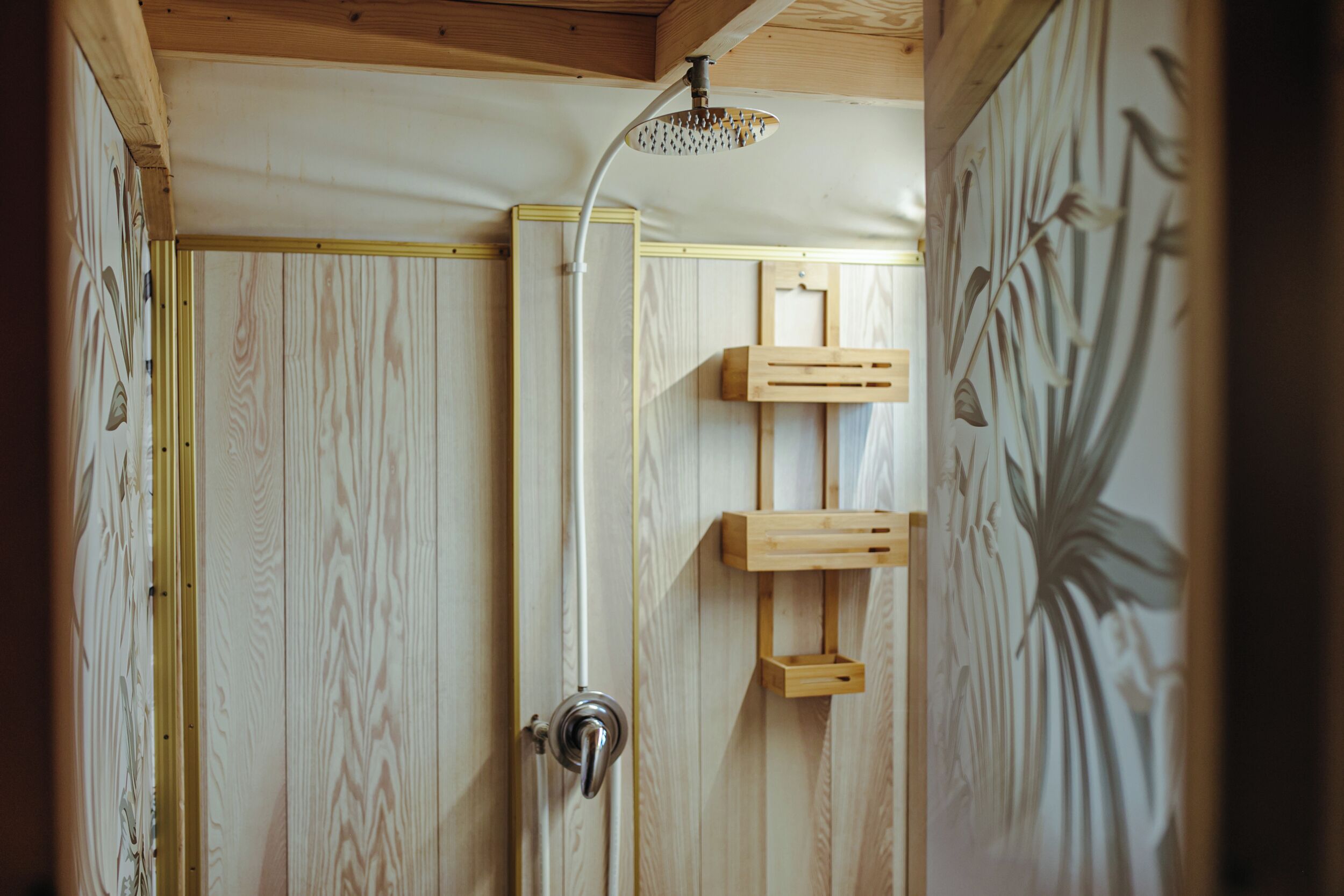 A wooden shower enclosure with a rain showerhead and a wooden shelf.