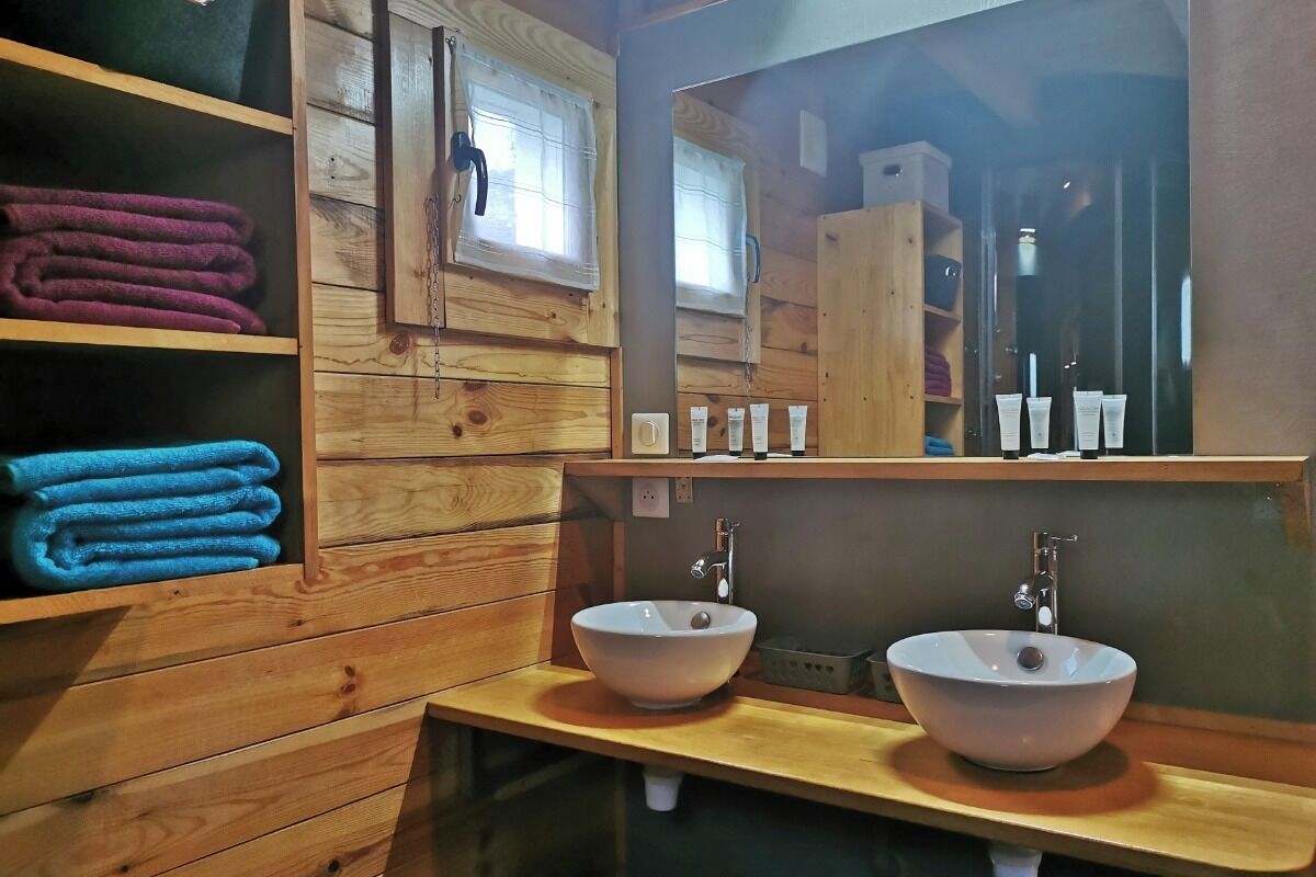 Un baño estilo cabaña de madera con dos lavamanos, un espejo y estantes con toallas dobladas.