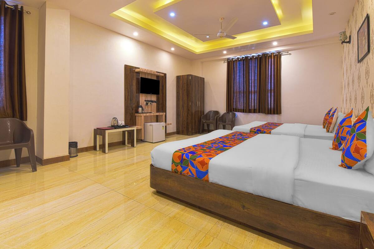 A hotel room with a large bed, a desk, a wardrobe, a television, and a ceiling fan.