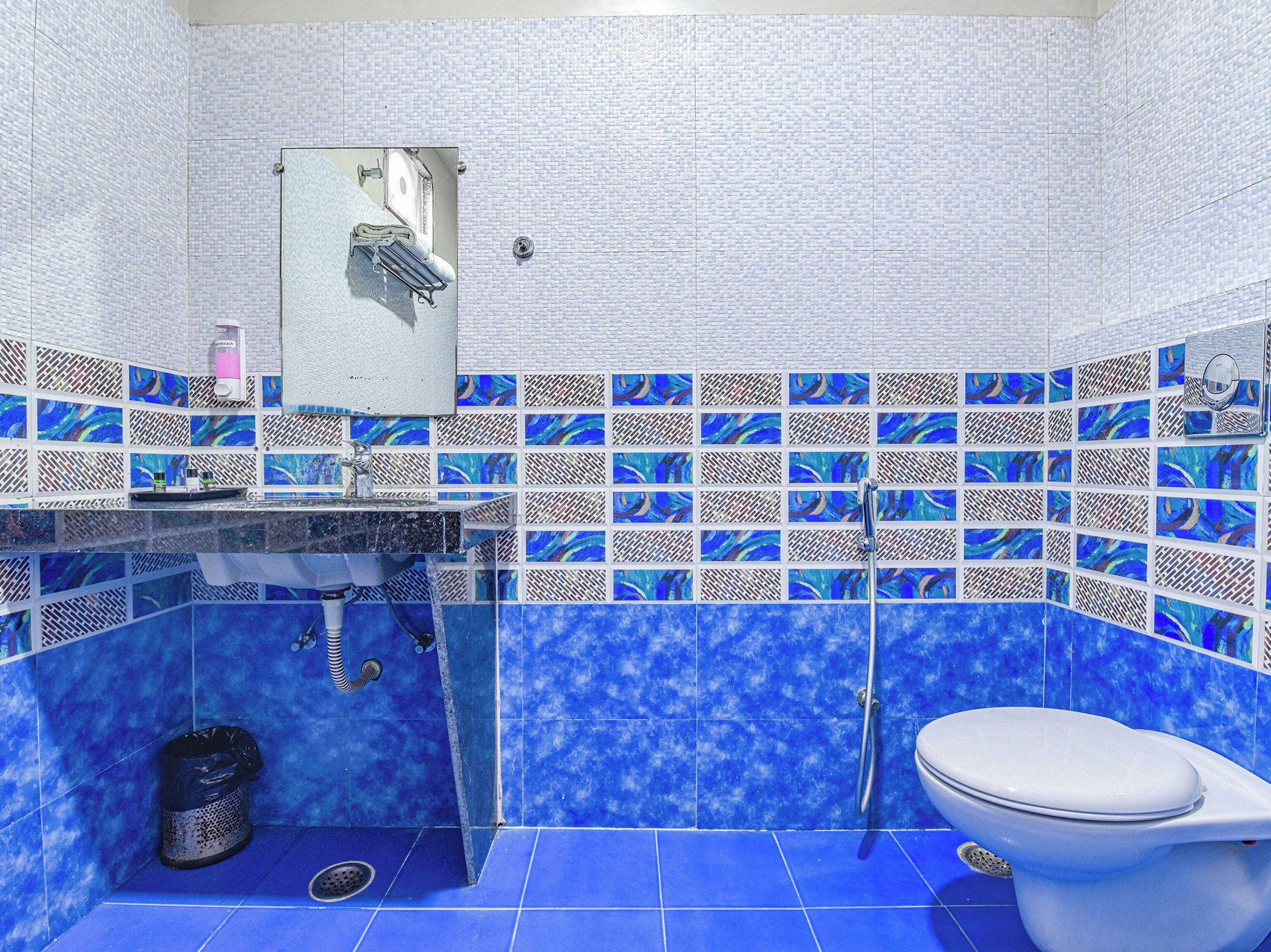 A bathroom with blue tiles, a sink, a toilet, and a shower.