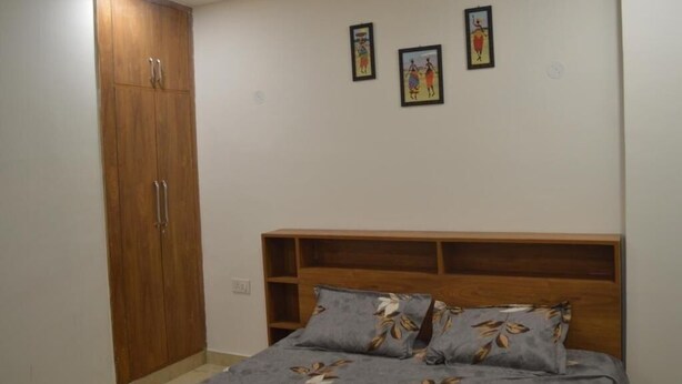 Un dormitorio con un armario de madera, una cama con ropa de cama floral y tres cuadros en la pared.