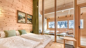 Habitación de cabaña de madera con cama, cortinas verdes y vistas al exterior.