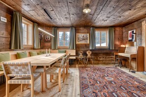 A rustic wooden interior with a long dining table, benches, and a patterned rug. - House Obdr Lech (Lech)