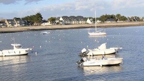 Un puerto deportivo con varias embarcaciones amarradas, una playa de arena y casas al fondo.
