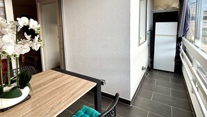 A modern kitchen with a refrigerator, a dining area with a wooden table and chairs, and a view of the city through large windows. - Air-conditioned apartment with parking and wifi 150m from the beach (Canet-en-Roussillon)