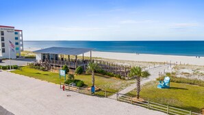 Ett semesterhotell vid stranden med en överbyggd paviljong, ett livräddartorn och utsikt över havet.