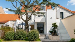 A modern house with a red-tiled roof, white exterior walls, and a well-maintained garden with shrubs and a tree. - Villa in Central Le Touquet with Air Conditioning and Wifi (Le Touquet-Paris-Plage)