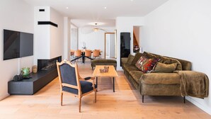 A modern living room with a fireplace, a sofa, a TV, and a dining area. - Villa in Central Le Touquet with Air Conditioning and Wifi (Le Touquet-Paris-Plage)