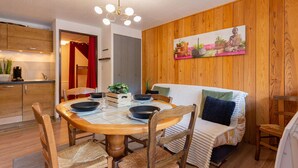 Un comedor acogedor con una mesa redonda de madera, sillas de mimbre y un candelabro moderno.