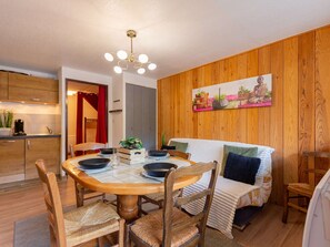 A cozy dining area with a round wooden table, wicker chairs, and a modern chandelier. - Apartment T2 Sleeps 4 - Saint-Lary Village - Free WiFi, Parking (Saint-Lary-Soulan)