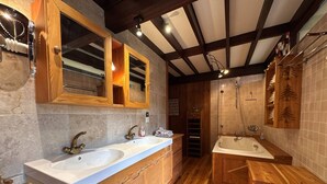 Een moderne badkamer met een houten wastafelmeubel, twee wastafels, een bad en een douche.