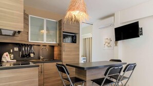Eine moderne Küche mit Essbereich, Holzschränken, einem Einbauofen und einem an der Wand montierten Fernseher.