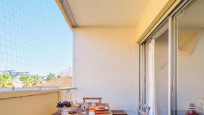 Ein Balkon mit Frühstückstisch, Blick auf die Stadt und einer dekorativen Wand.