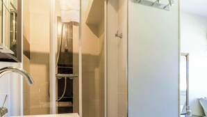 Ein Badezimmer mit Dusche, Waschbecken und Handtuchhalter.