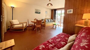 A cozy room with a bed, a dining table with chairs, a sofa, and a wooden floor. - Mountain Studio in Claux, 4 people, close to slopes & shops (Vars)