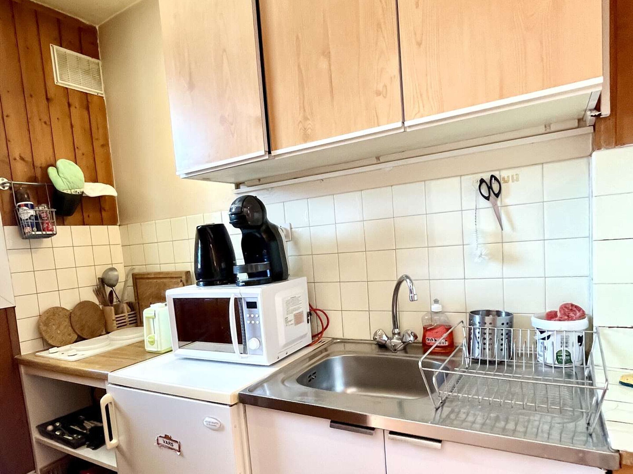 A kitchen with a microwave, coffee maker, sink, and various utensils.