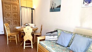 A cozy living area with a wooden dining table, chairs, a sofa with floral upholstery, and a radiator. - Mountain Studio in Claux, 4 people, close to slopes & shops (Vars)