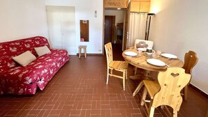 A cozy room with a red floral sofa, a wooden dining table set for four, and a wooden bunk bed in the background. - Mountain Studio in Claux, 4 people, close to slopes & shops (Vars)