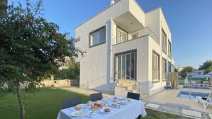 Uma casa moderna de dois andares com área de jantar montada no exterior.